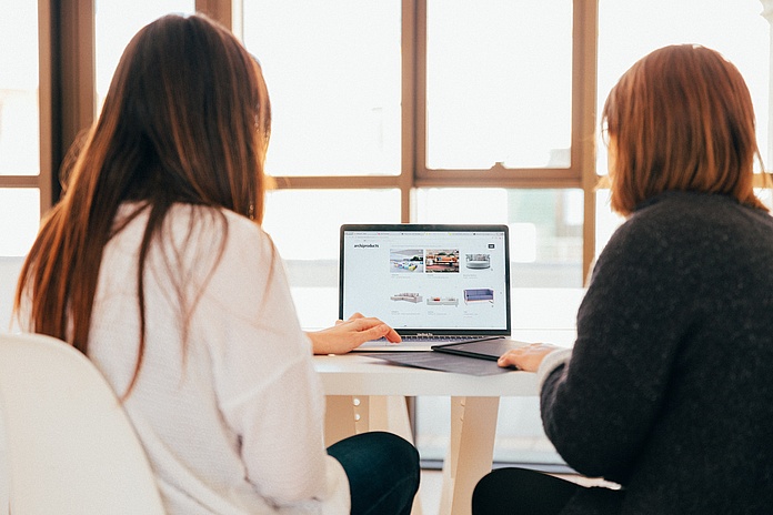 Zwei Frauen sitzen am Schreibtisch und arbeiten