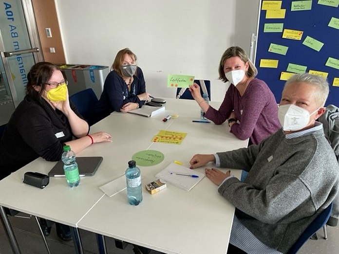 Personen sitzen am Tisch bei einem Workshop