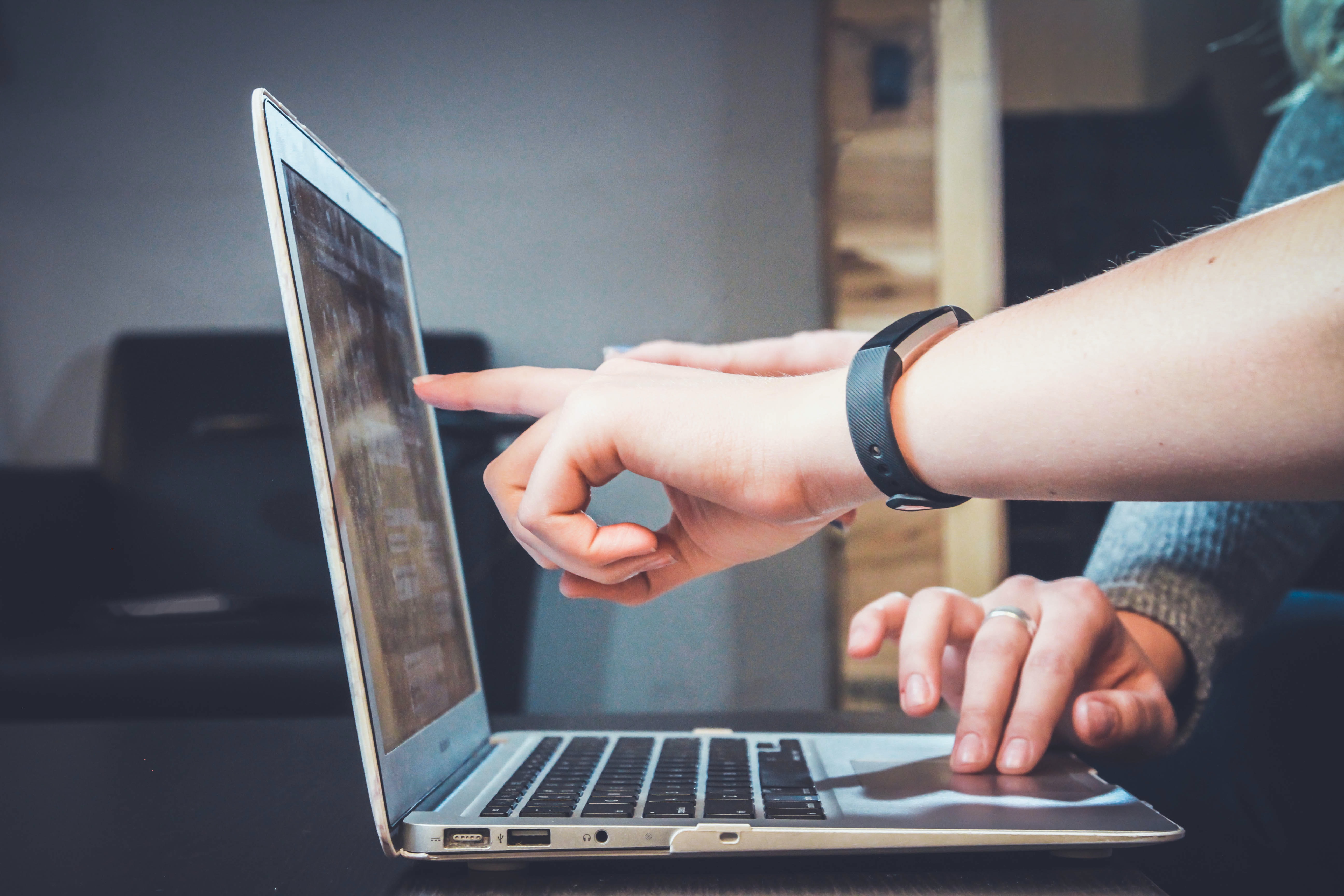 Eine Hand zeigt auf den Bildschirm eines Laptops